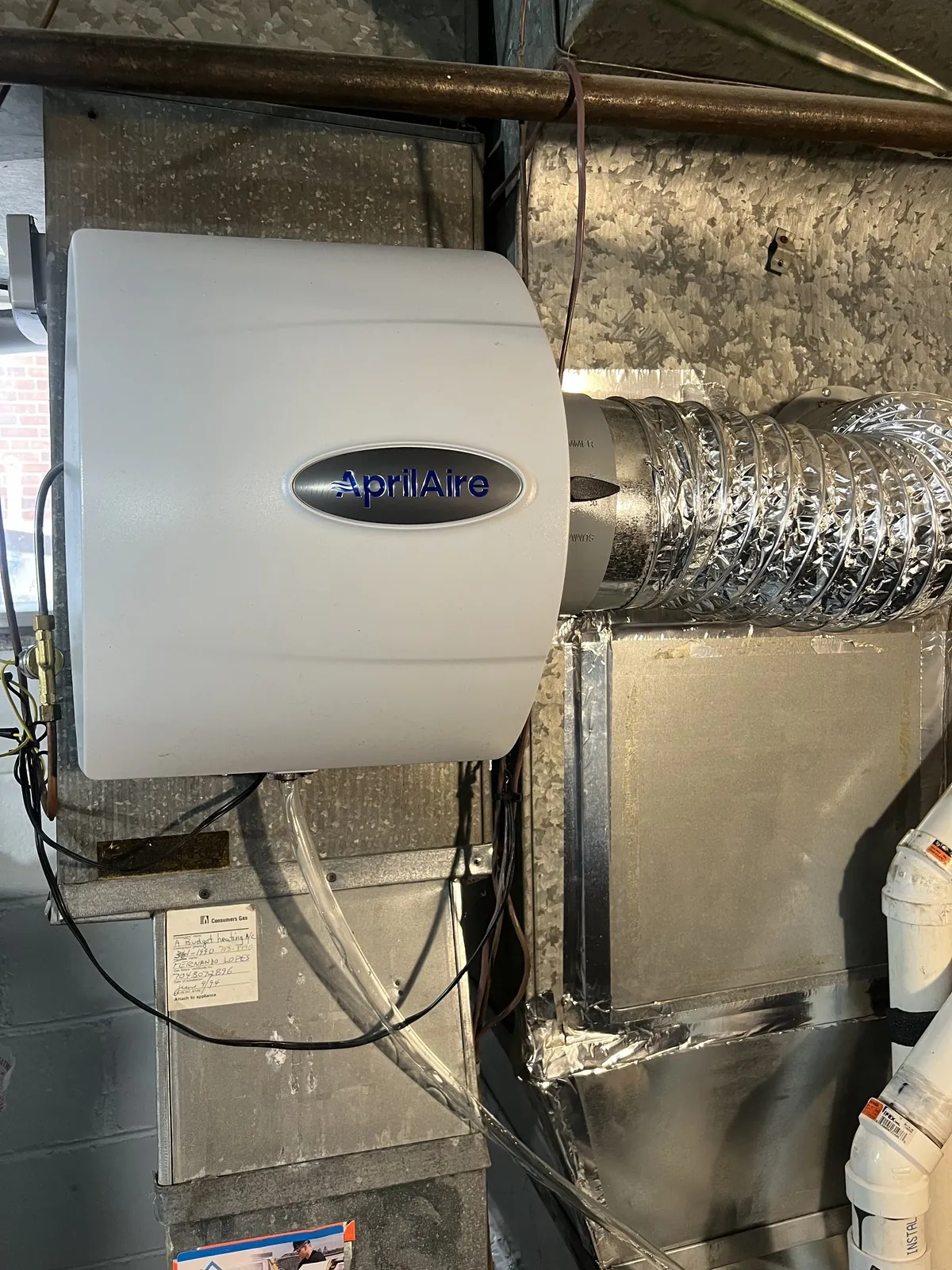 Bypass humidifier mounted on the return duct above a gas furnace in a basement