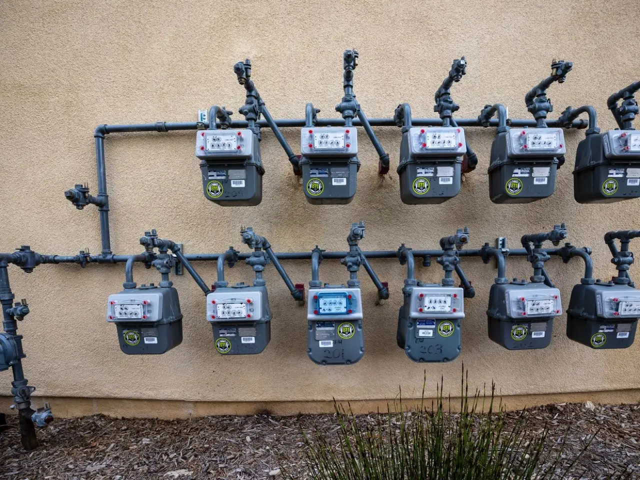 Bank of natural gas meters and branch piping on an apartment building wall