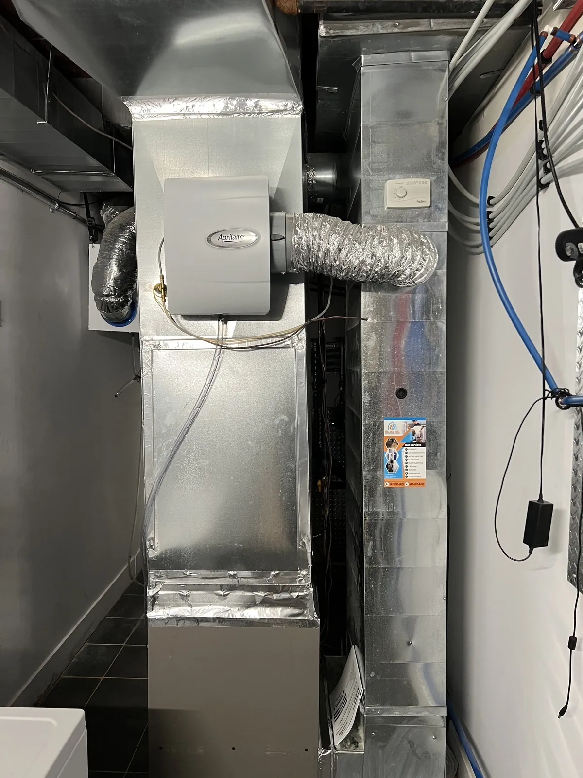 Furnace and evaporator coil installed in a basement with new sheet metal ductwork running from the cabinet.