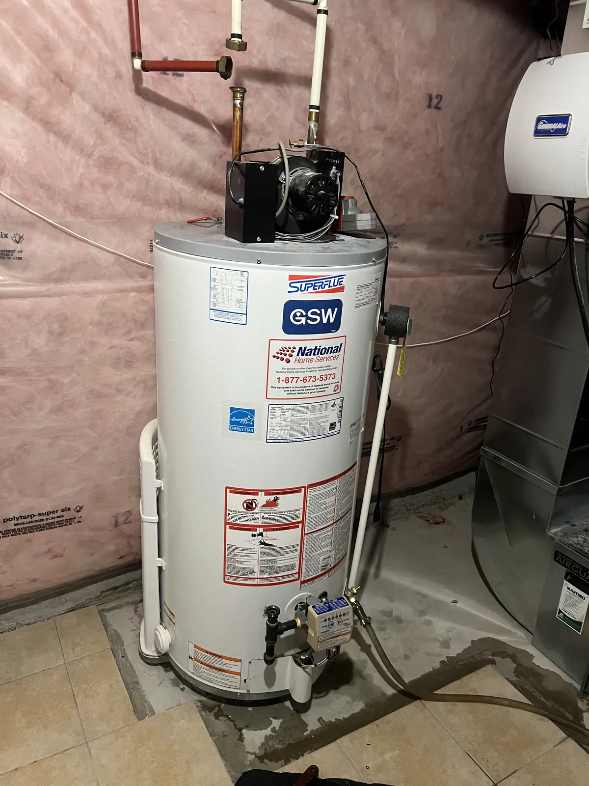 New gas hot water tank installed against an insulated basement wall
