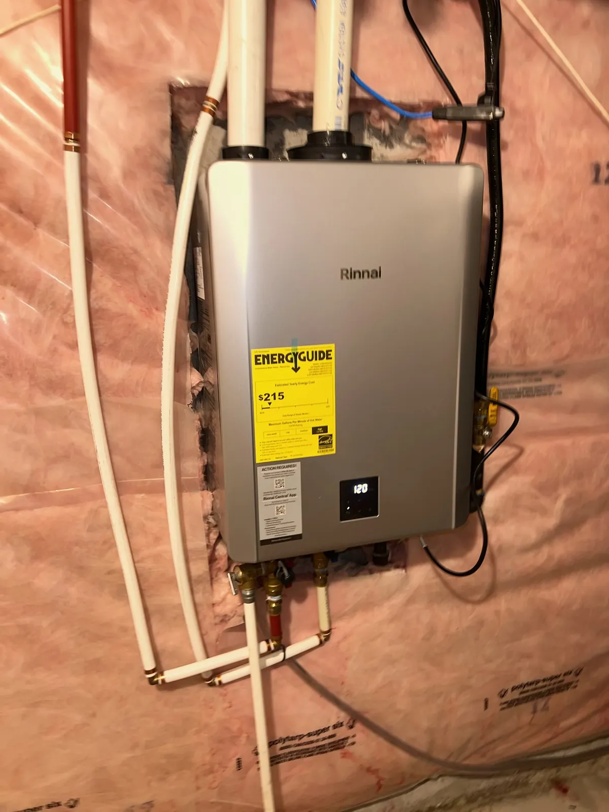 Tankless water heater mounted on an insulated basement wall with its venting and piping run to it