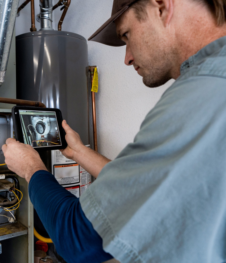 HVAC technician inspecting a furnace with a tablet during heating maintenance in Mississauga